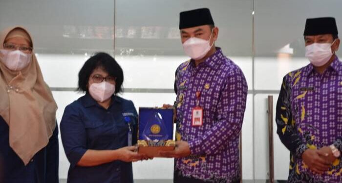 Kepala Cabang BPJS Kesehatan Tigaraksa, Sudiyanti menyerahkan penghargaan UHC kepada Wakil Bupati Tangerang Mad Romlie. JEK